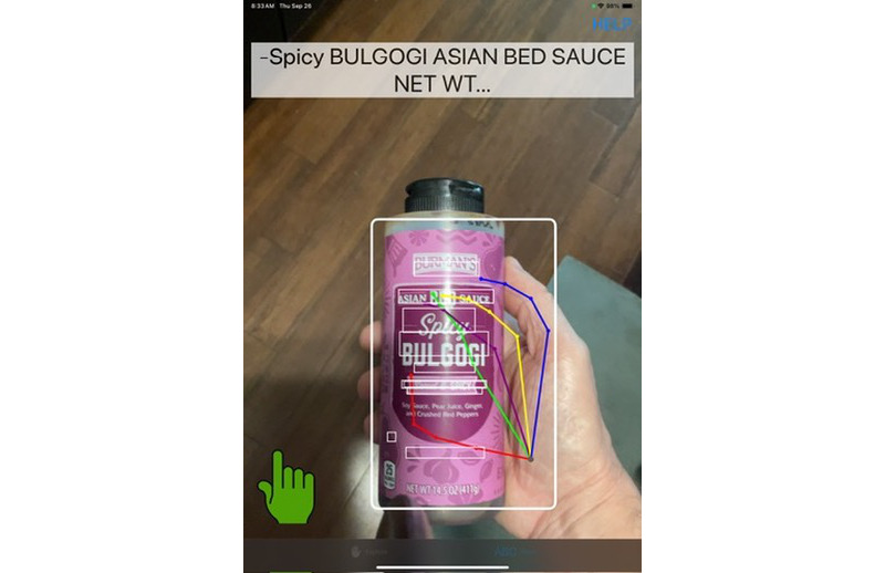 The Lite app running on an iPad and reading "Spicy Bulgogi Asian Sauce" from a bottle held in a hand.